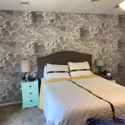 A bedroom with a wallpapered accent wall.
